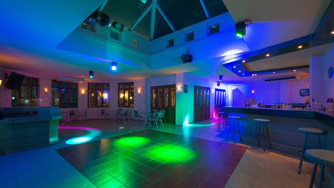 Innenansicht der Disco im Iberostar Creta Panorama & Mare Hotel mit bunten Lichtern und Sitzgelegenheiten.