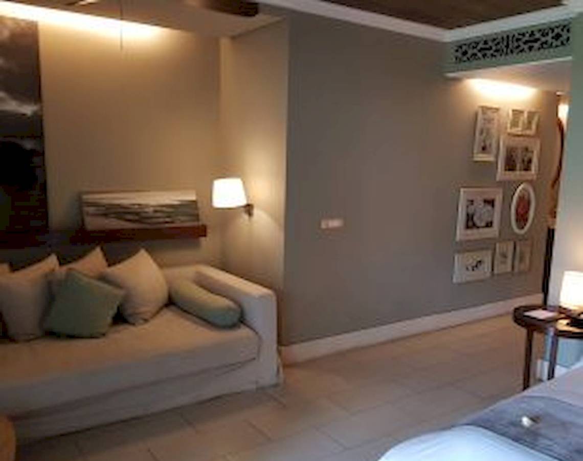 Schlafzimmer im JW Marriott Mauritius Resort mit Bett, Sofa, Nachttisch und dekorierten Wänden.
