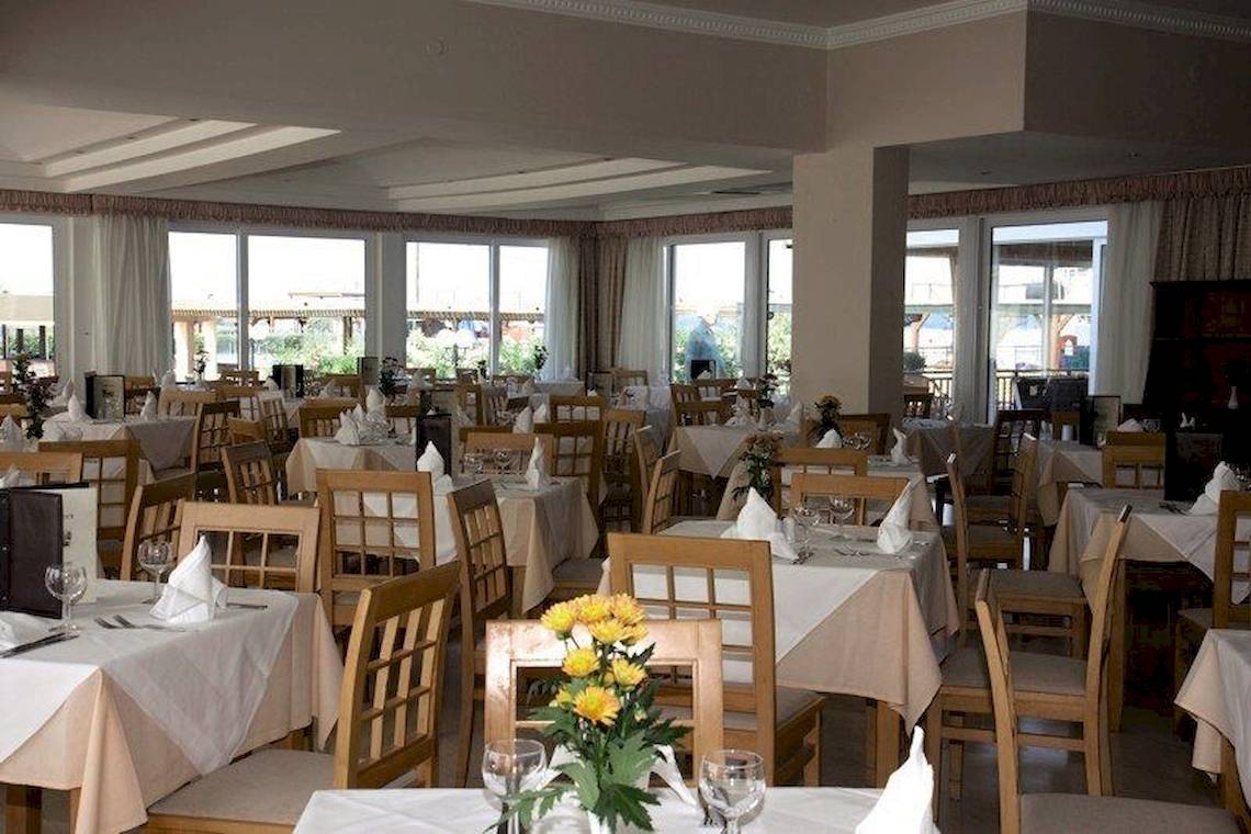 Innenansicht des Restaurants im Astir Beach Hotel mit gedeckten Tischen und gelben Blumen.
