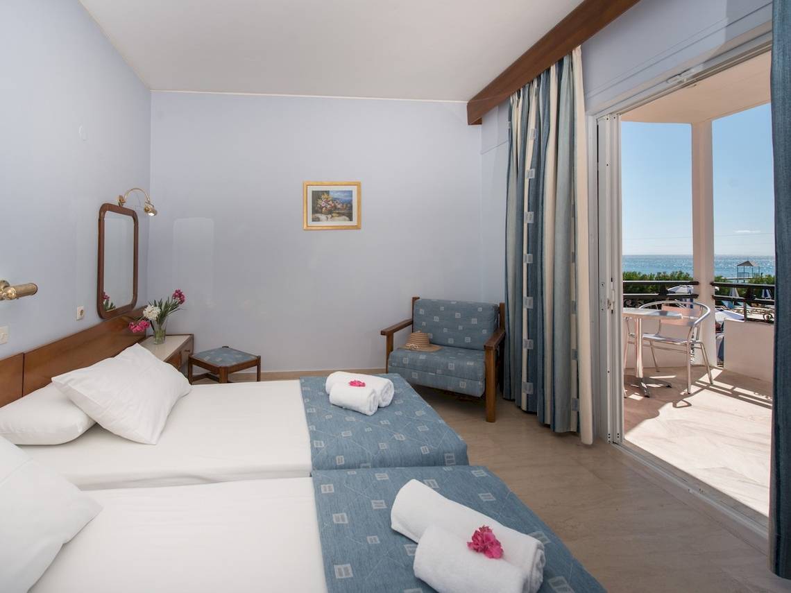 Zimmer mit Meerblick im Astir Beach Hotel auf Zakynthos mit zwei Betten, Balkon, Tisch und Stühlen.