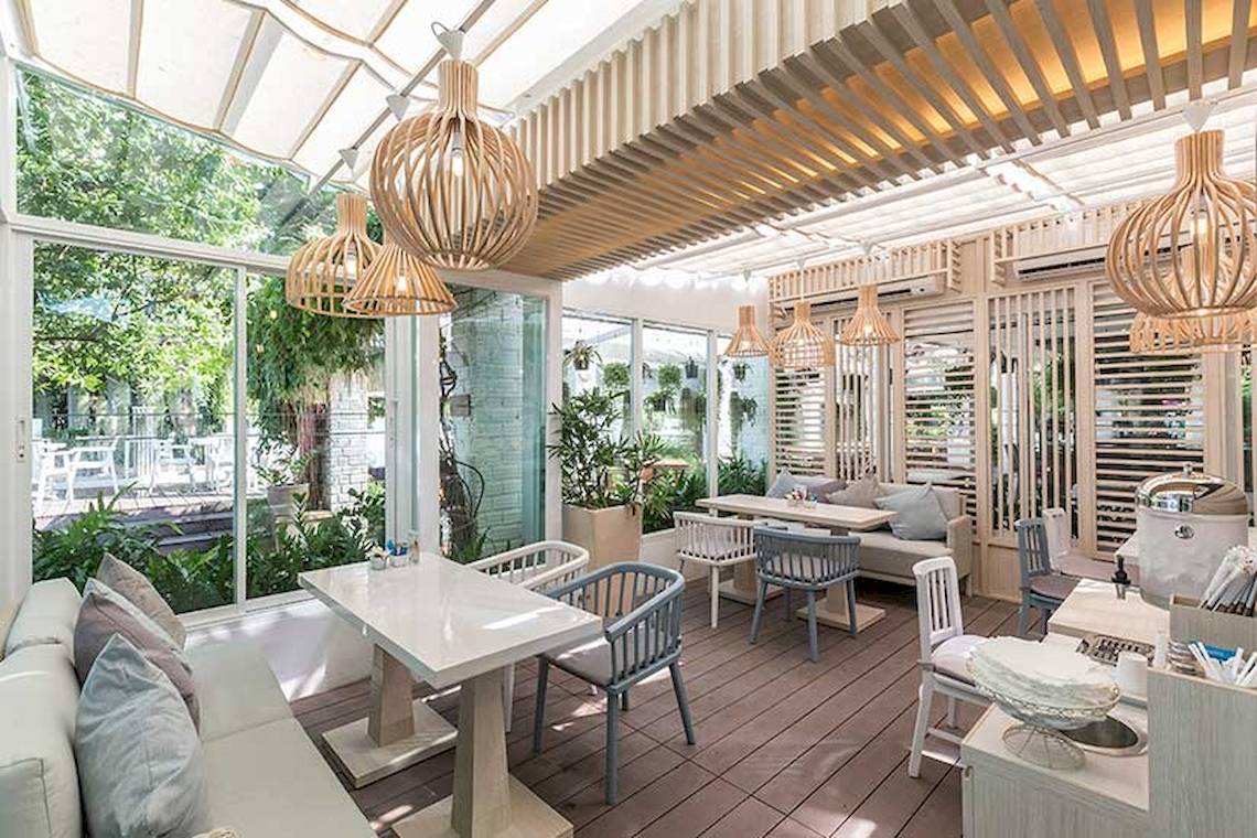 Innenbereich des Cape Panwa Hotels mit Tischen, Stühlen und Pflanzen.