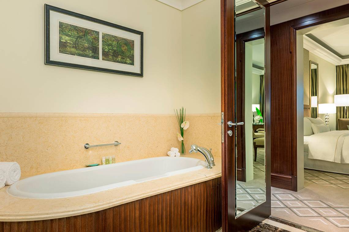Badezimmer einer Suite im Westin Dubai Mina Seyahi mit Badewanne, Spiegel und gerahmtem Bild an der Wand.