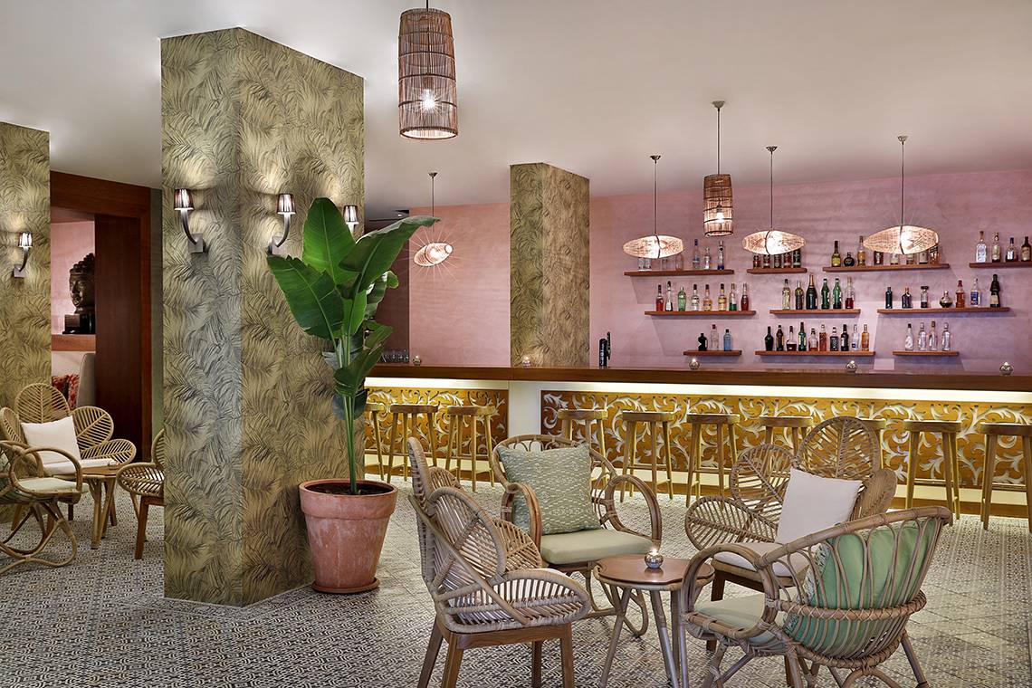 Innenbereich des Westin Dubai Mina Seyahi Beach Resort & Marina Hotel mit Bar, Rattanmöbeln und Pflanzen.