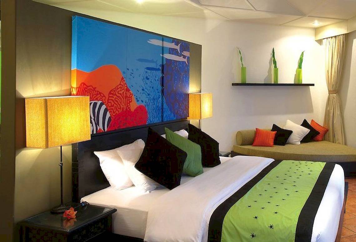 Hotelzimmer im Angsana Velavaru mit großen Gemälden, bequemem Bett und Sofa