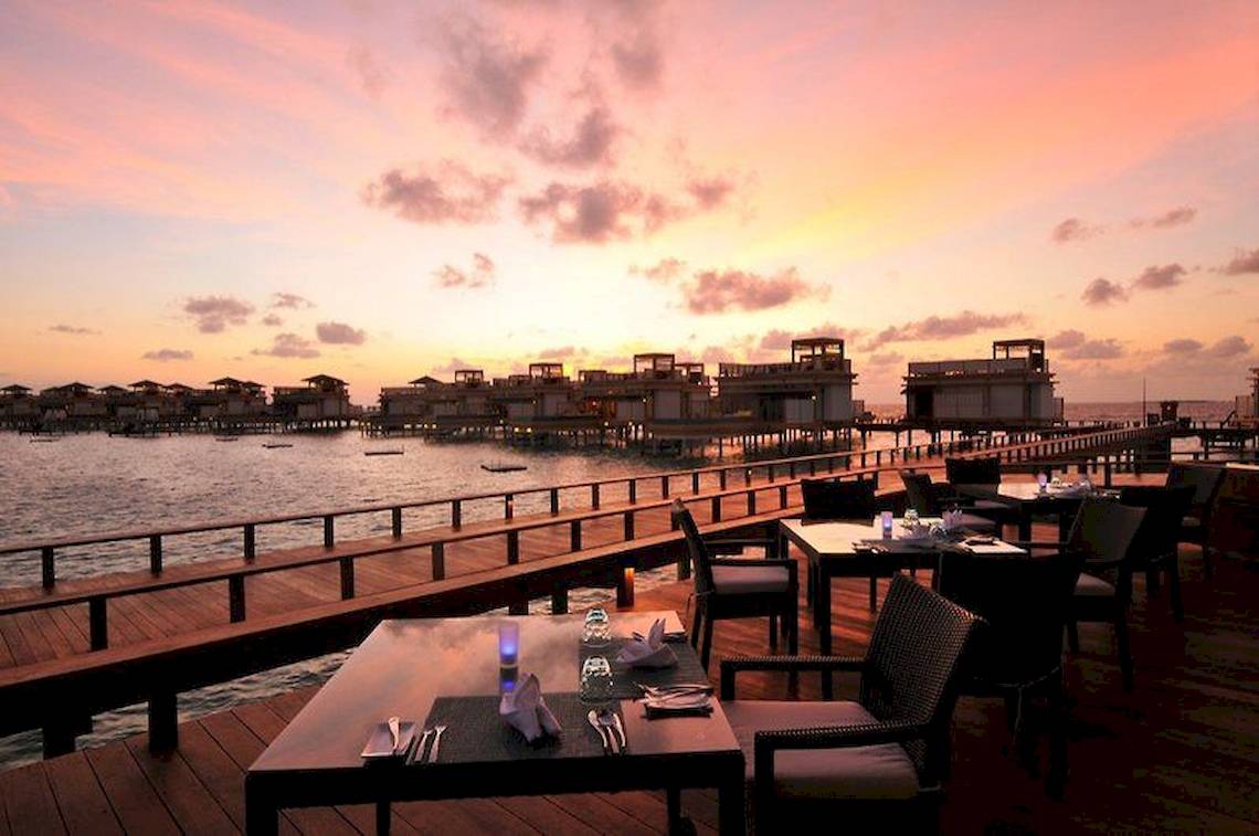 Sonnenuntergang mit Blick auf das Angsana Velavaru Resort und Wasservillen.