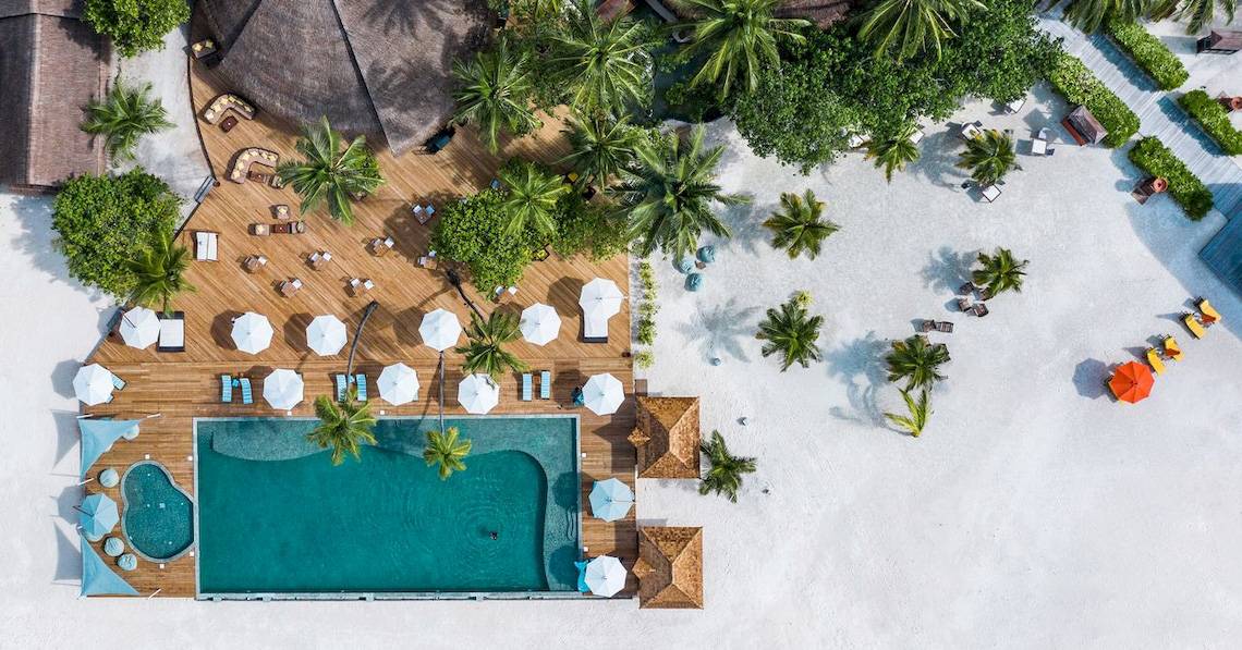 Angsana Velavaru Hotel - Luftaufnahme des Pools und Strands mit vielen Sonnenschirmen und Palmen