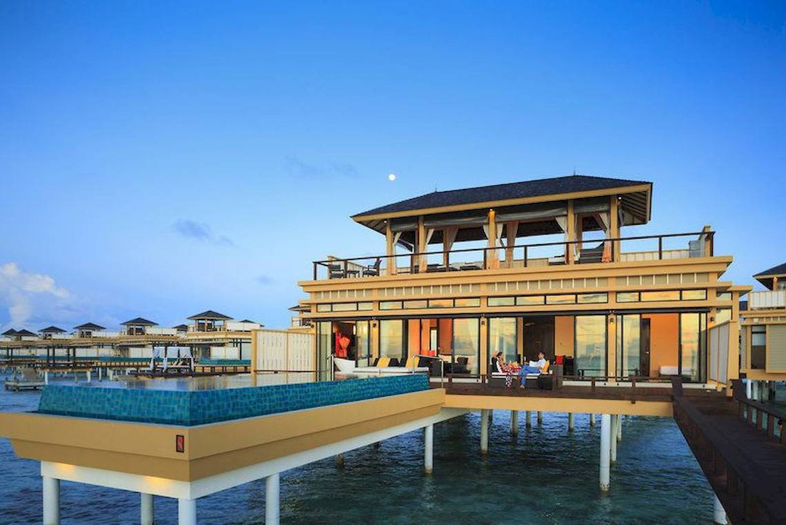 Außenansicht der Wasservilla im Angsana Velavaru Hotel mit Pool und zwei Personen auf der Terrasse.