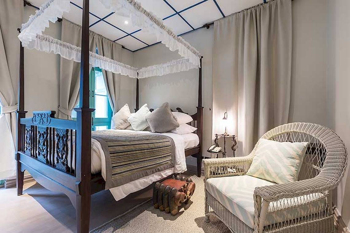 Schlafzimmer im Cape Panwa Hotel mit einem vierposterbett, kissen und einem stuhl