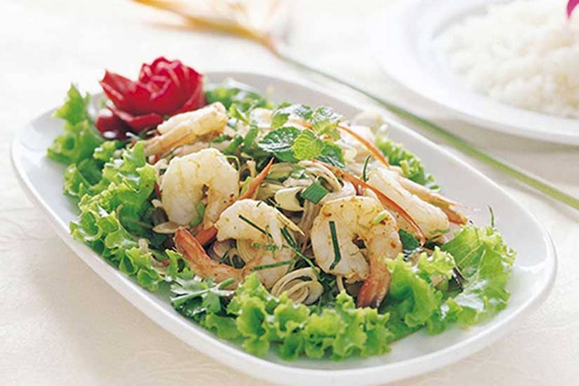 Gegrillte Garnelen auf Salat serviert auf einem weißen Teller mit einer roten Rose