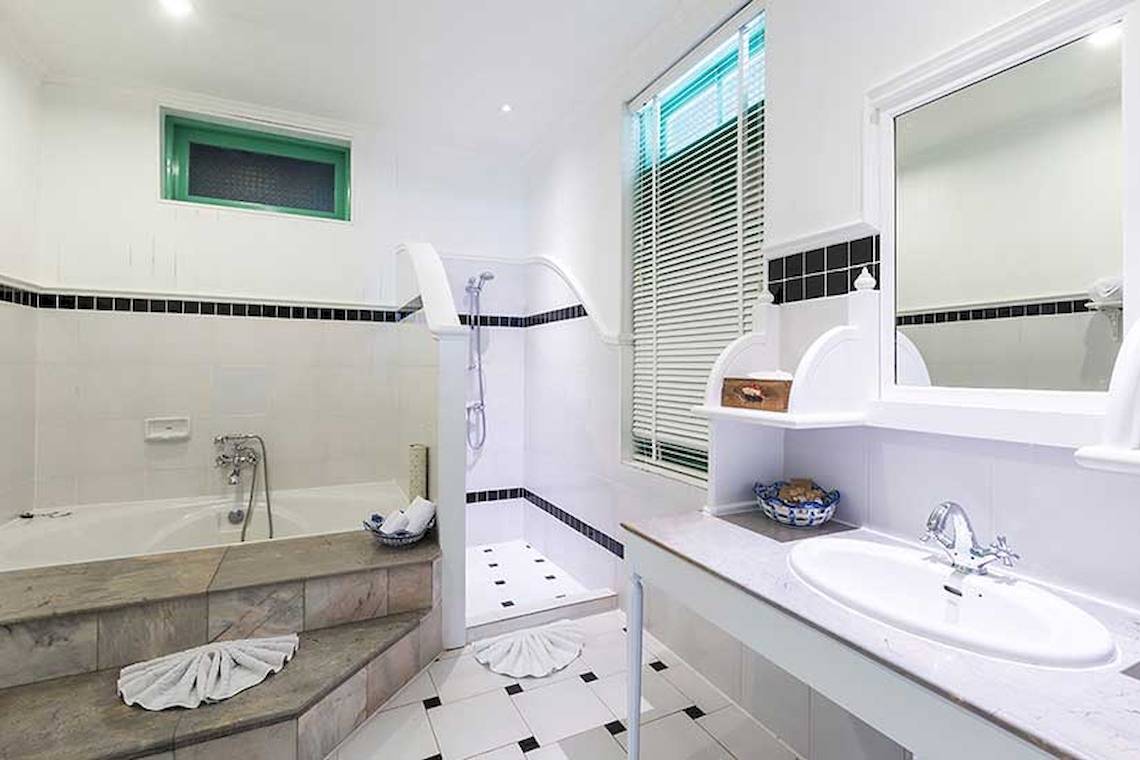 Badezimmer im Cape Panwa Hotel mit Badewanne, Dusche, Waschbecken und Spiegel.