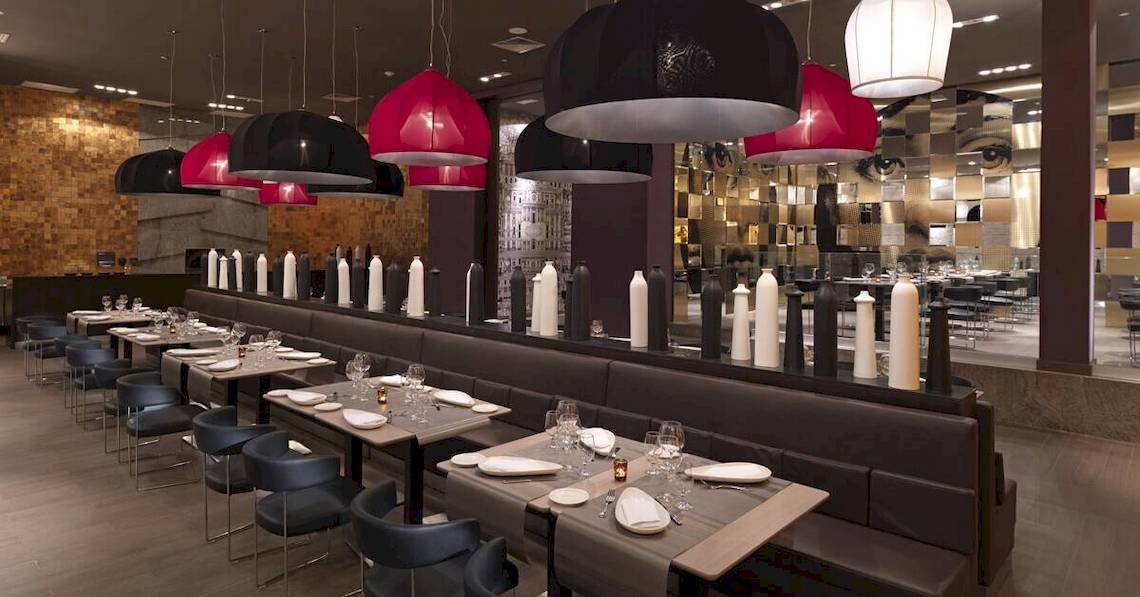 Inneneinrichtung des Restaurants im Paradisus Playa del Carmen mit Tisch und Stühlen, roten und schwarzen Hängelampen.