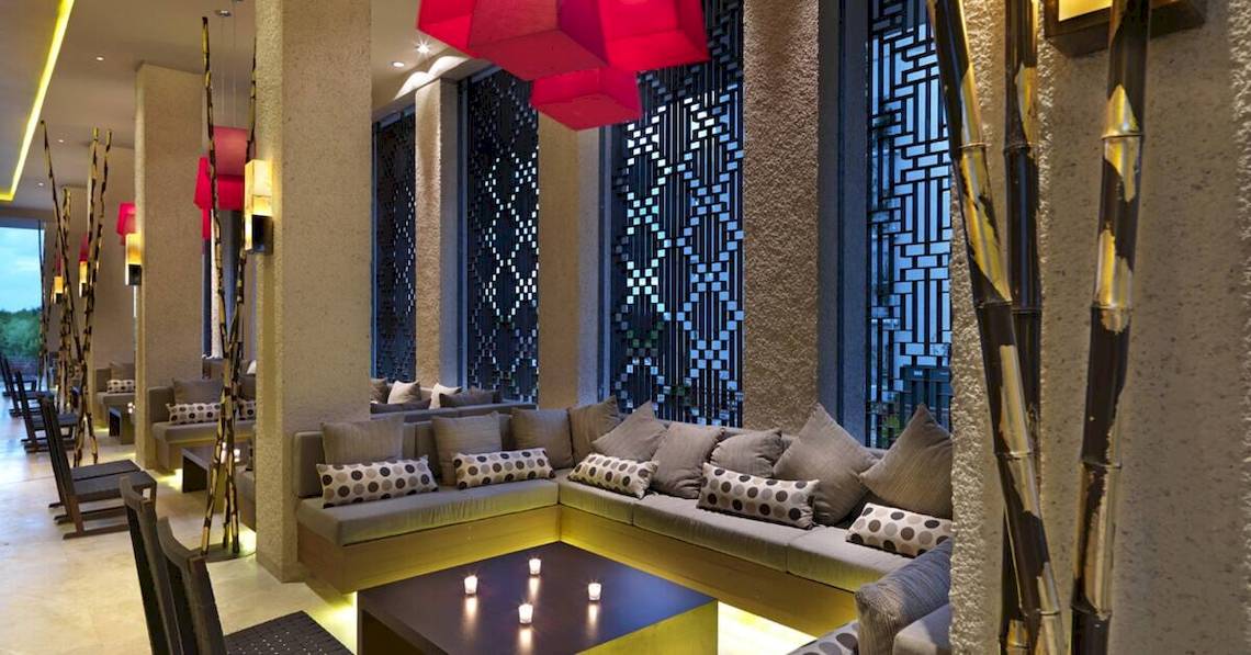 Loungebereich im Paradisus Playa del Carmen Hotel mit Sofas, Kerzen und modernen Kunstwerken.