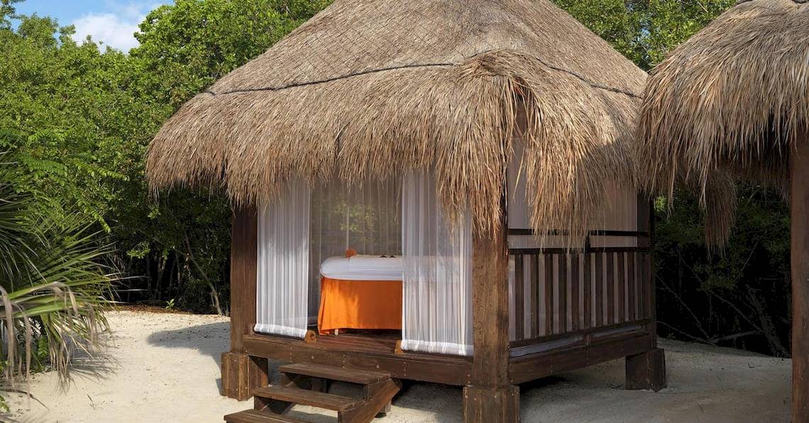 Strandhütte im Paradisus Playa del Carmen Hotel mit weißem Vorhang und oranger Bettdecke