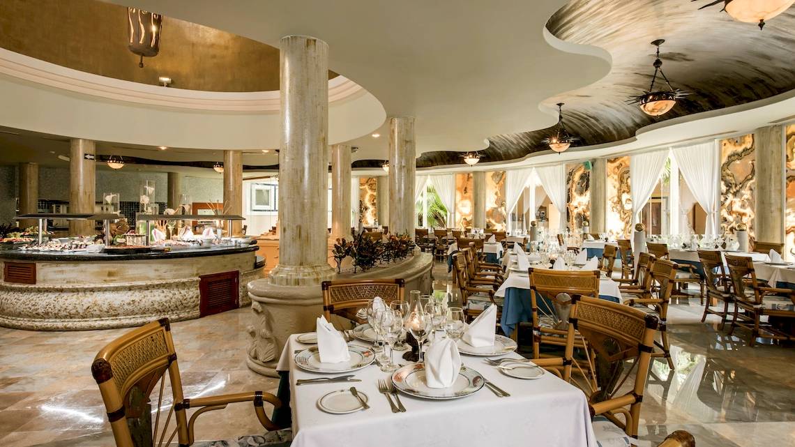 Innenansicht des Restaurants im Iberostar Paraiso del Mar Hotel mit geräumigen Tischen und Stühlen, einem eleganten Buffet und einer geräumigen Atmosphäre.
