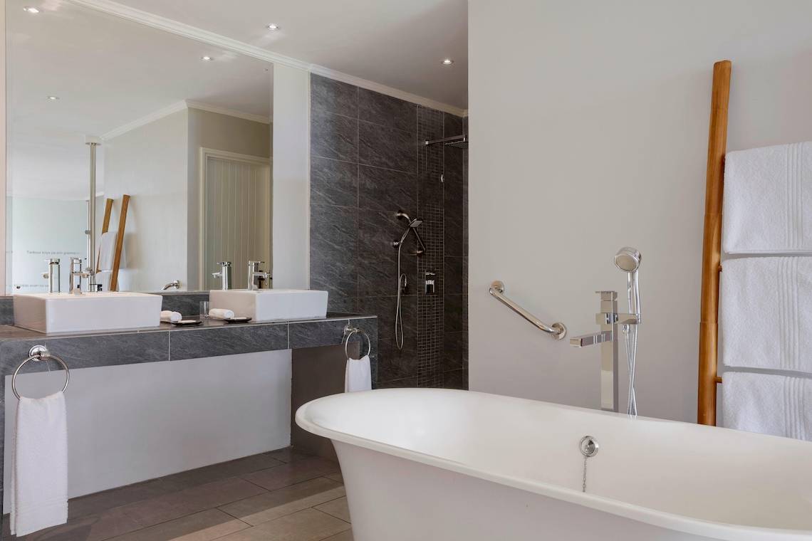 Badezimmer im Fisherman's Cove Resort mit Badewanne, Waschbecken und Handtüchern.