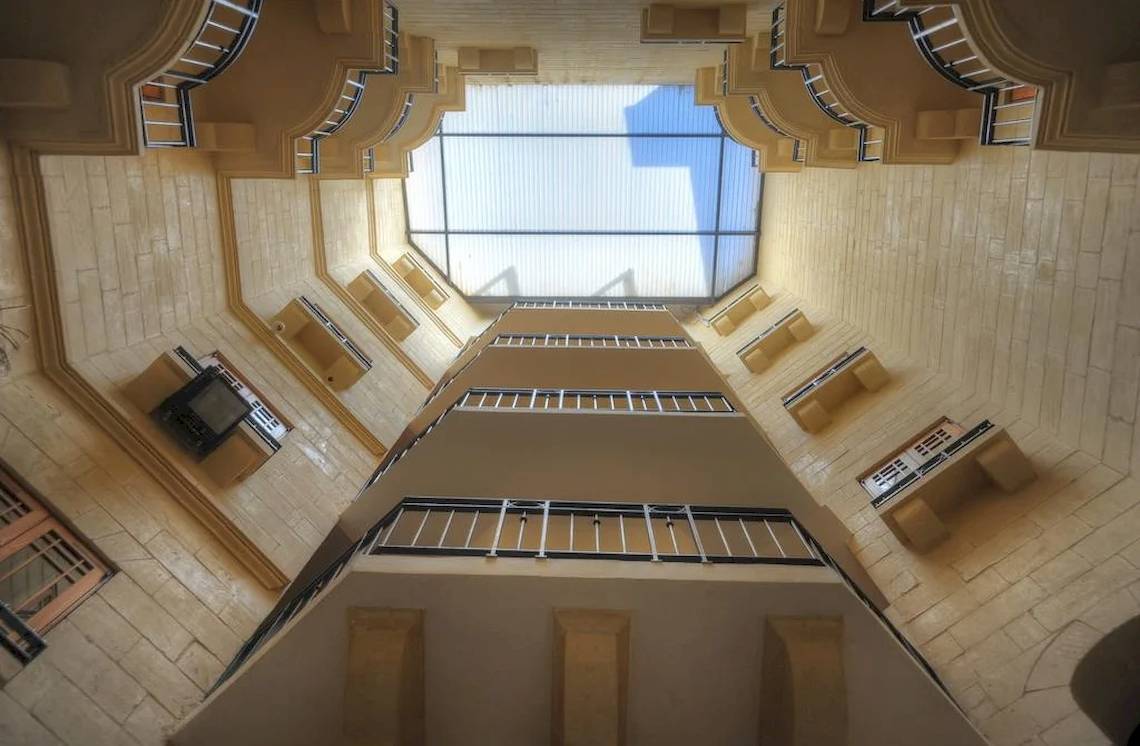 Innenansicht von oben des Saint Patrick's Hotel Gozo mit Betonwänden und Metallgeländern.