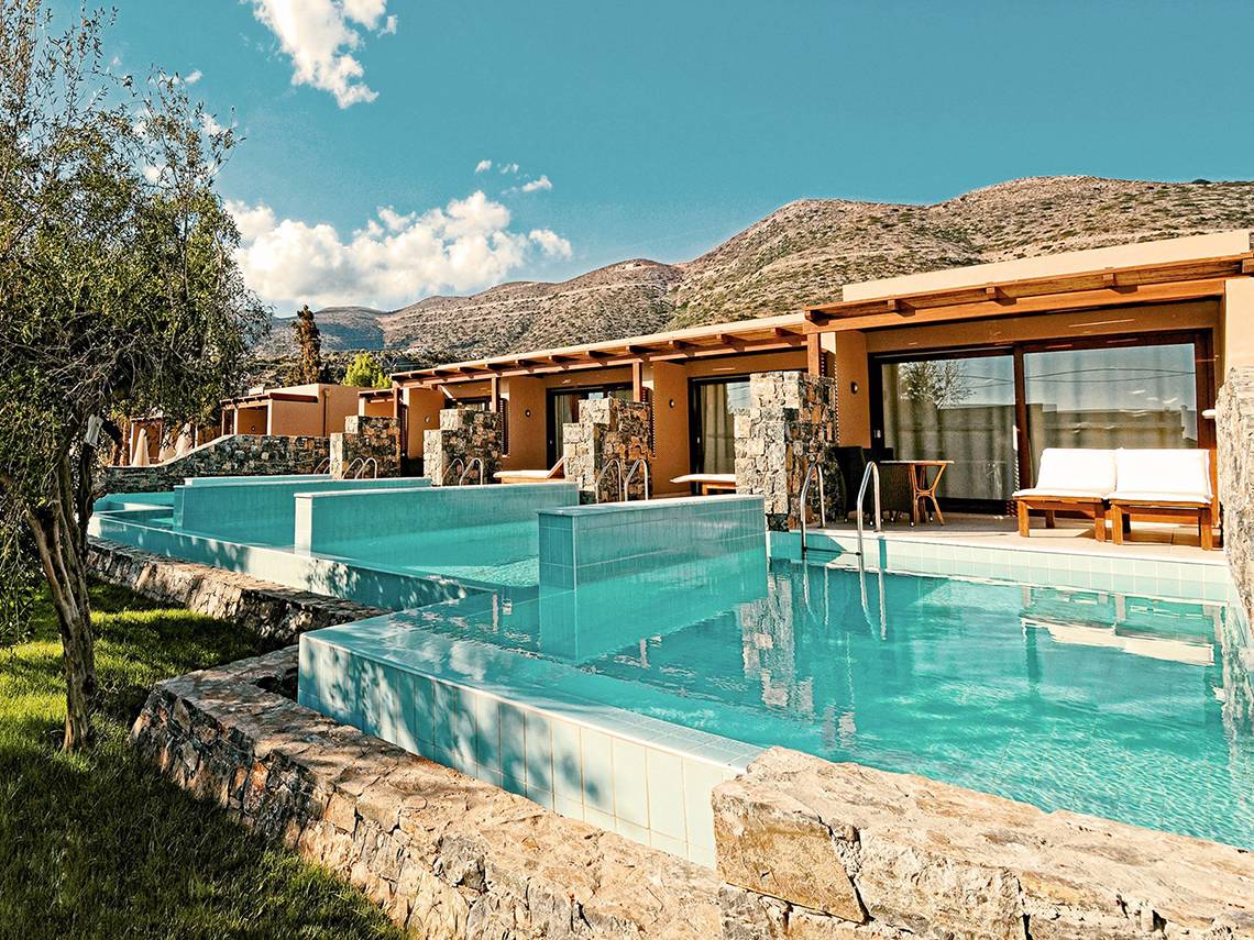 Außenpool des Blue Sea Beach Affiliated by Melia Hotels mit steinernem Rand und Bergen im Hintergrund.