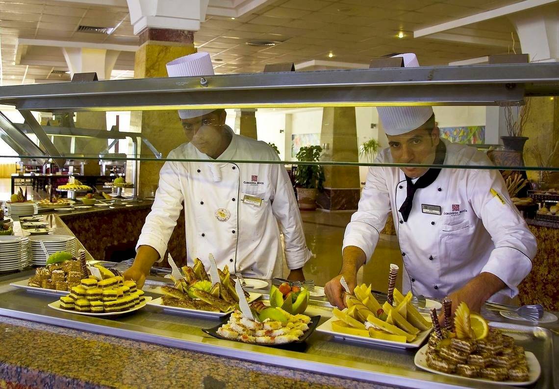 Zwei Mitarbeiter eines Gorgonia Beach Resorts servieren Essen in einem Restaurant.