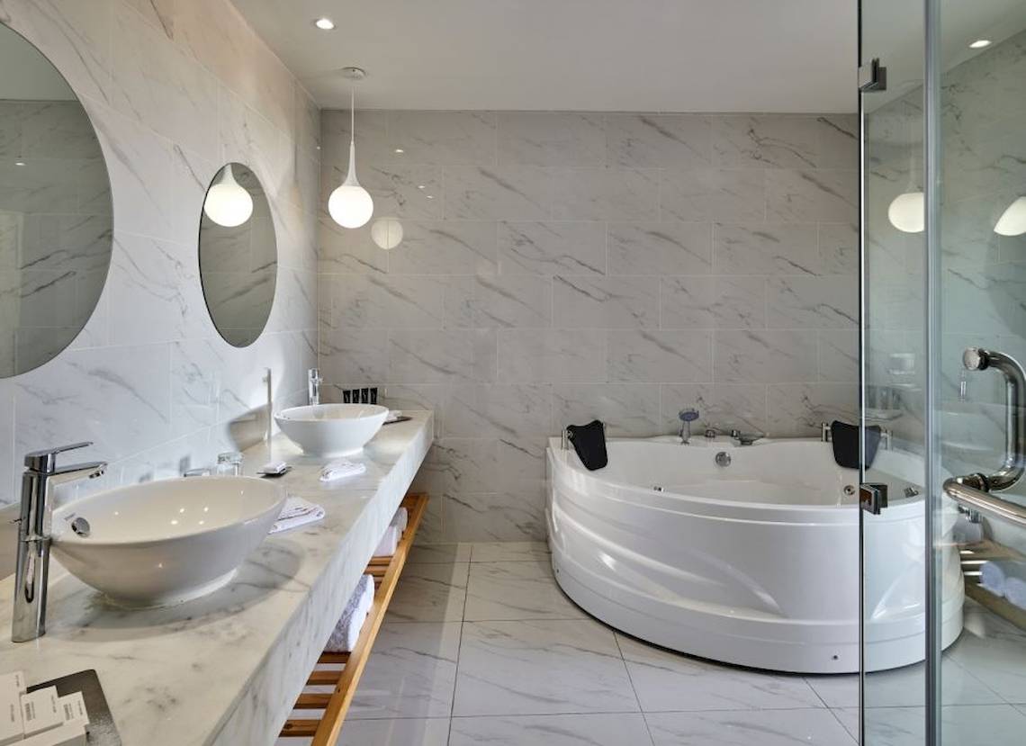 Badezimmer mit Badewanne und Doppel-Waschbecken im Steigenberger Pure Lifestyle Hotel
