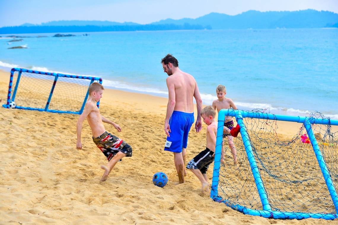 Vater und Kinder spielen Fußball am Strand des Briza Beach Resort