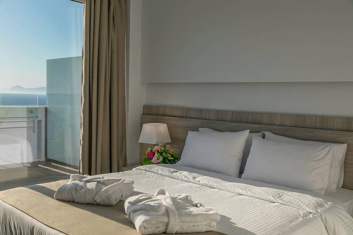 Akti Imperial Deluxe Resort & Spa Zimmer mit Meerblick, Bett mit weißen Laken und Handtüchern.