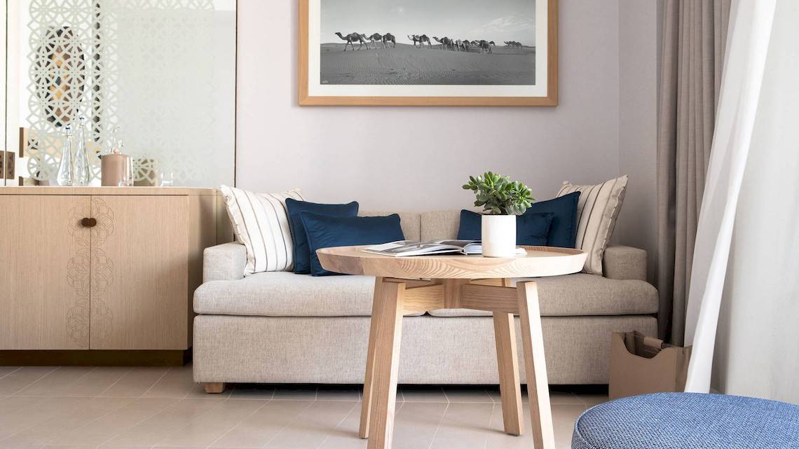 Ein Wohnzimmer im Jumeirah at Saadiyat Island Resort mit einem Sofa, einem Tisch und einer Wand mit einem Kamelbild.