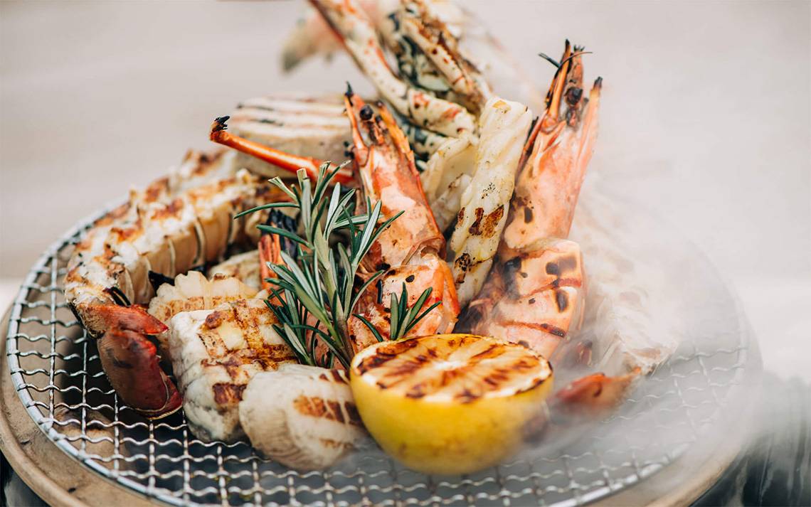 Gegrillter Meeresfrüchte-Platter mit Zitrone und Rosmarin auf einem Grillrost