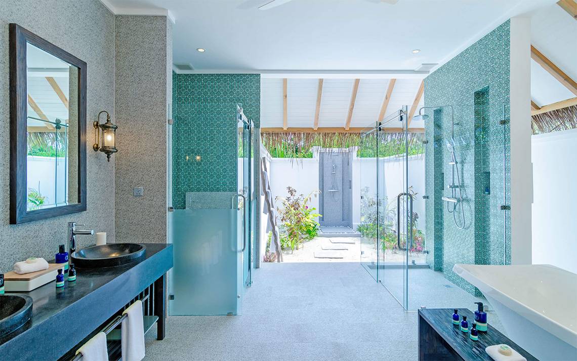 Badezimmer im Finolhu Baa Atoll Maldives Hotel mit blauen Fliesen und Glasdusche.