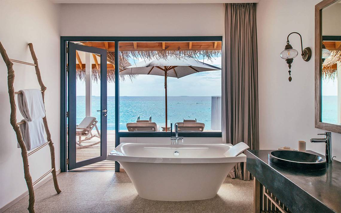 Badezimmer der Suite im Finolhu Baa Atoll Hotel mit Blick auf das Meer.