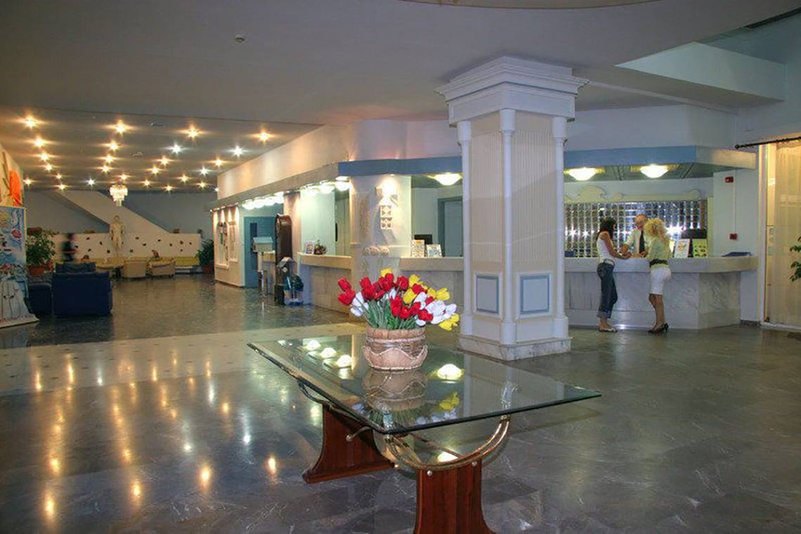 Empfangsbereich des Atlantis Beach Hotel auf Kos mit Blumenarrangement und zwei Frauen am Empfang.