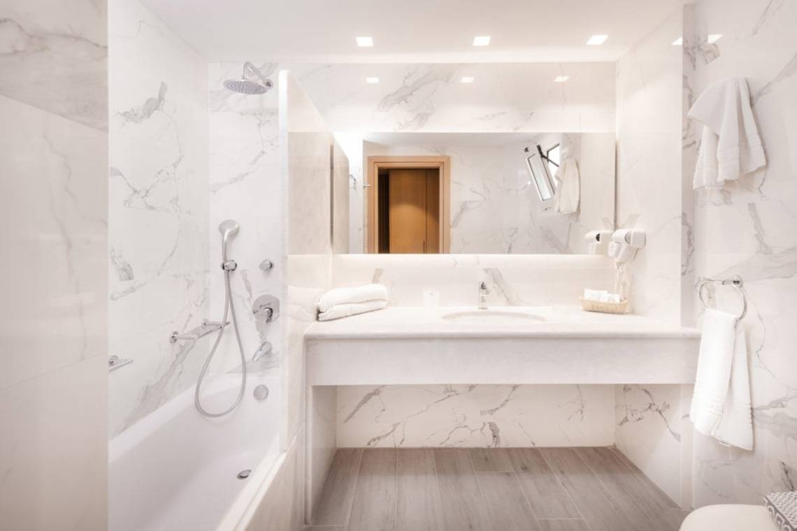 Innenansicht eines Badezimmers im Horizon Beach Resort mit weißen Marmorfliesen und einer Badewanne.