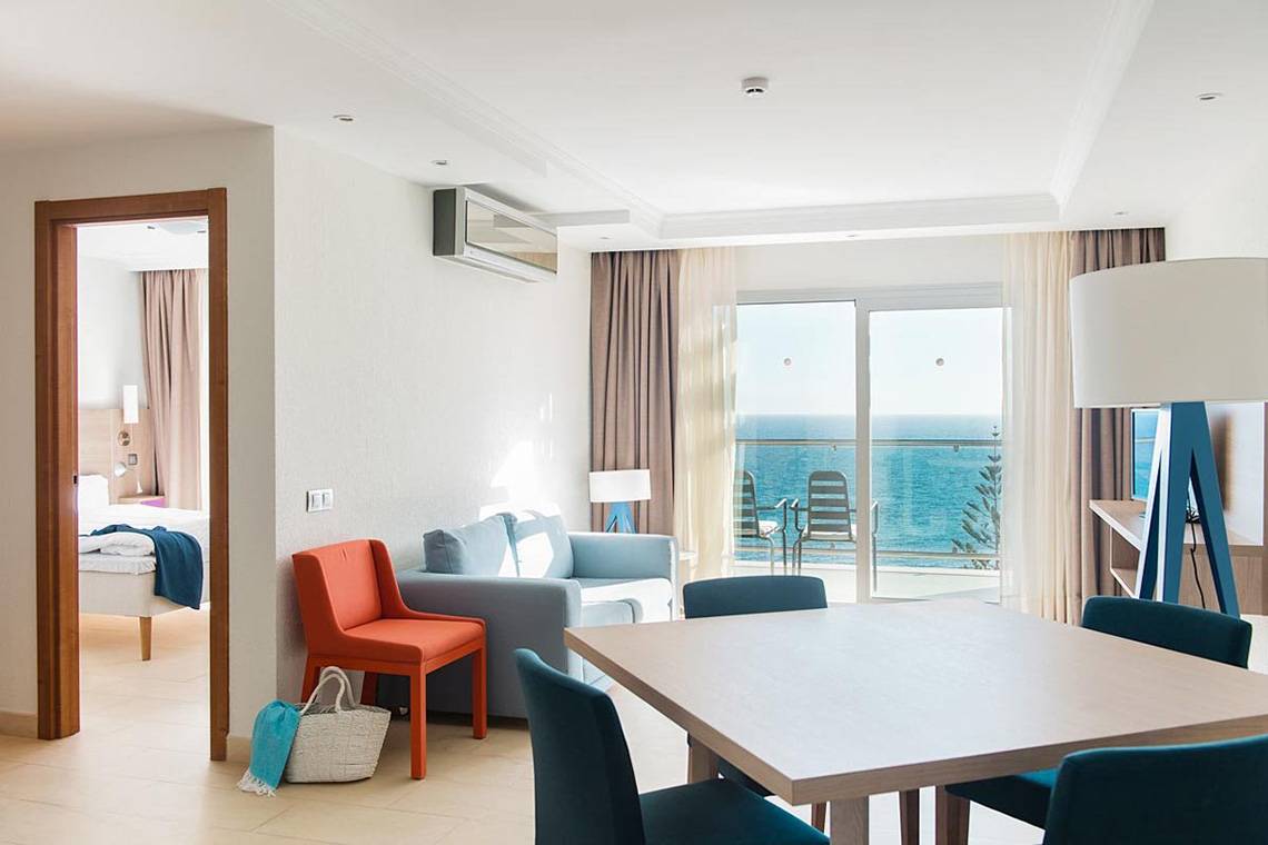 Ein modernes Hotelzimmer mit Blick auf das Meer und einer Sitzecke.