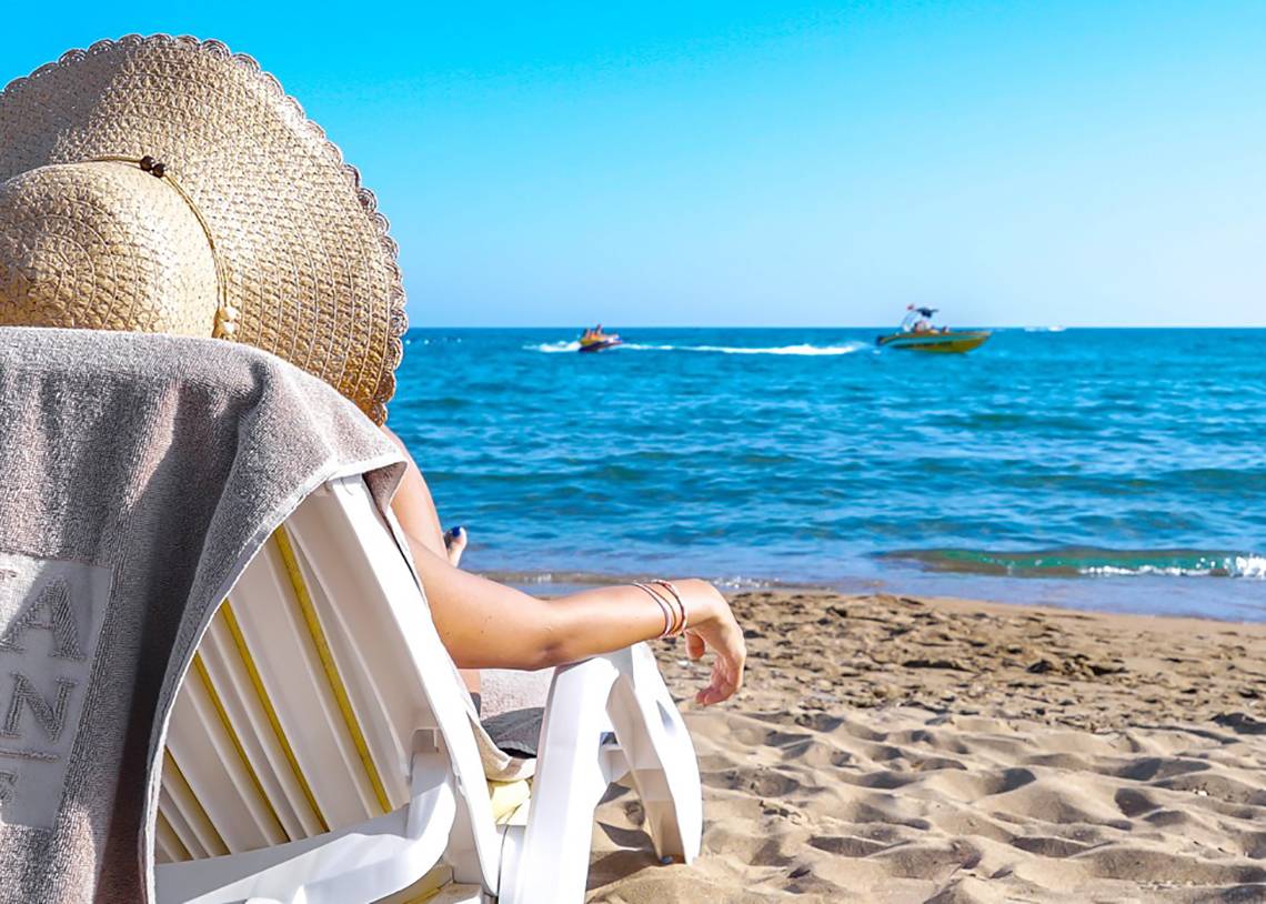 Person auf dem Strandstuhl mit Blick auf das Meer und Speedbooten, Kamelya Aishen K Club