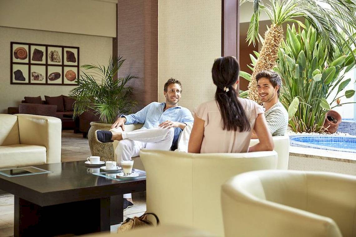 Drei Personen sitzen im Robinson Kyllini Beach Hotel in der Lounge.