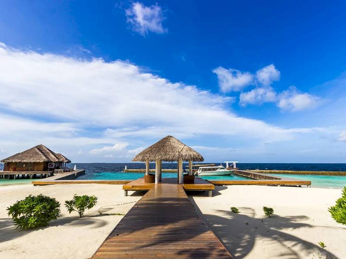 Amaya Kuda Rah Hotel Strand mit hütten und blauem Meer im Hintergrund