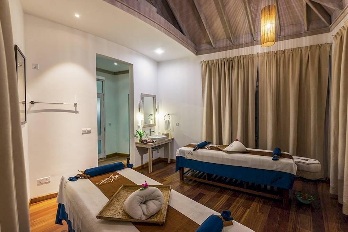 Massageraum im Hotel Amaya Kuda Rah mit zwei Massagetischen und einem Waschbecken.