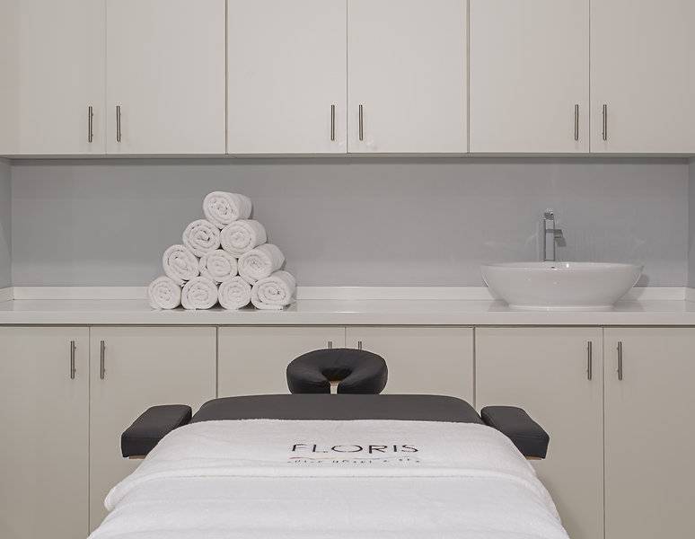 Ein Massagestuhl mit einem weißen Handtuch und einem Waschbecken in einem Zimmer