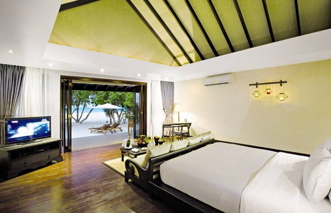 Innenansicht eines Hotelzimmers im Atmosphere Kanifushi Maldives mit Blick auf das Meer.