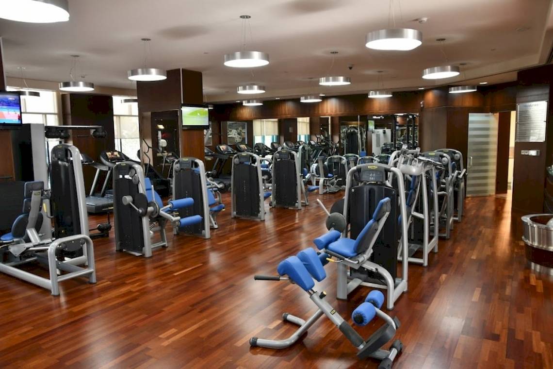 Fitnesscenter im Al Ain Rotana Hotel mit vielen Trainingsgeräten und Holzböden.