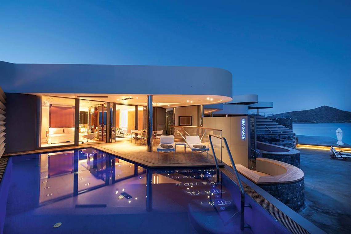 Nachtansicht des Elounda Beach Hotel & Villas mit beleuchtetem Pool und Außenbereich.