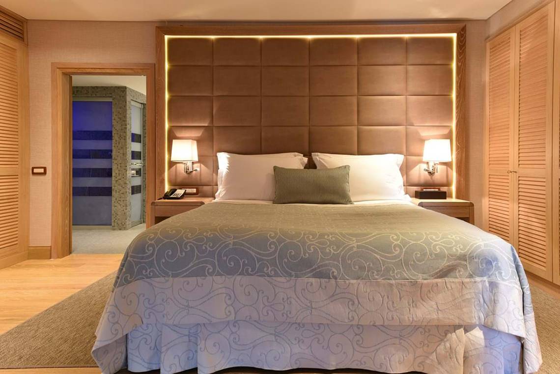 Schlafzimmer im Elounda Beach Hotel & Villas mit gemusterter Bettwäsche und Nachttischen.