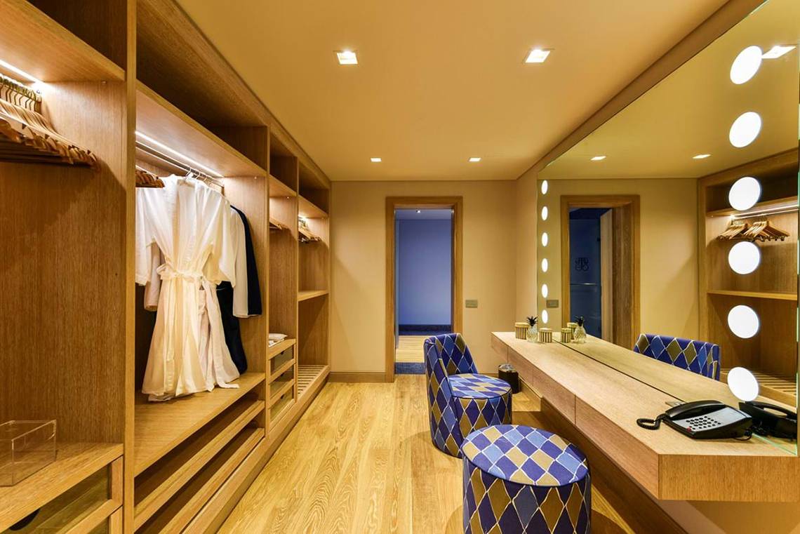 Elounda Beach Hotel & Villas: Innenansicht eines Kleiderschranks in einem Zimmer mit blauen Stühlen und einem langen Schreibtisch.