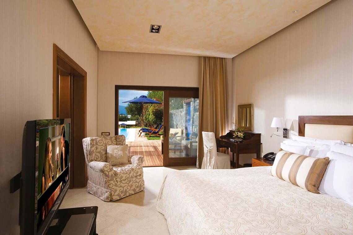 Schlafzimmer im Elounda Beach Hotel & Villas mit Fernseher, Bett und Zugang zur Terrasse