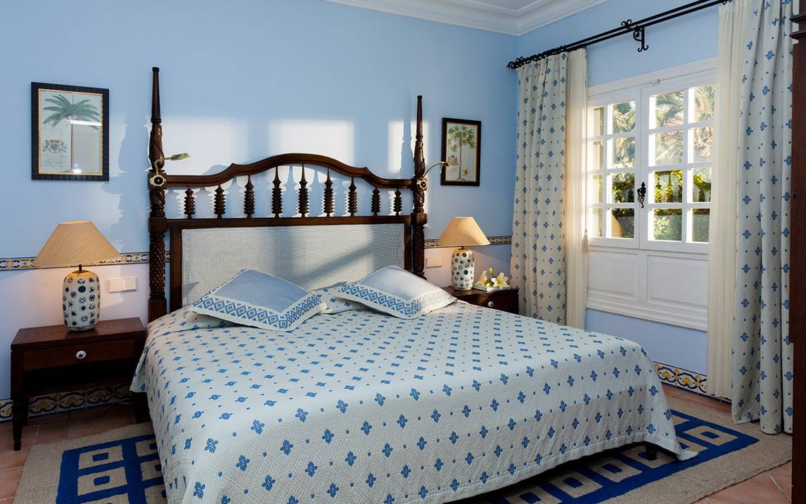 Schlafzimmer im Seaside Grand Hotel Residencia mit blauer Bettwäsche und blauen Kissen.