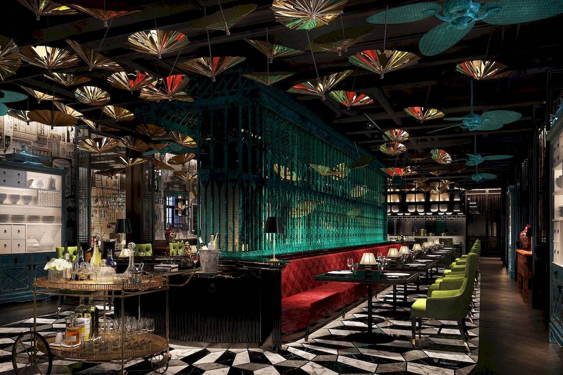 Innenansicht des W Muscat Hotels mit Bar, grünen Stühlen und roten Sofas.