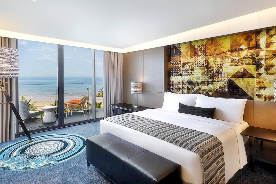 Ein modernes Hotelzimmer im W Muscat mit Meerblick, großem Bett und Balkon.