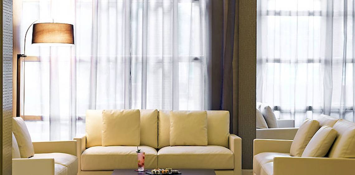 Wohnzimmer im Barcelo Palmeraie Hotel mit beigefarbenen Sofas und weißem Vorhang.