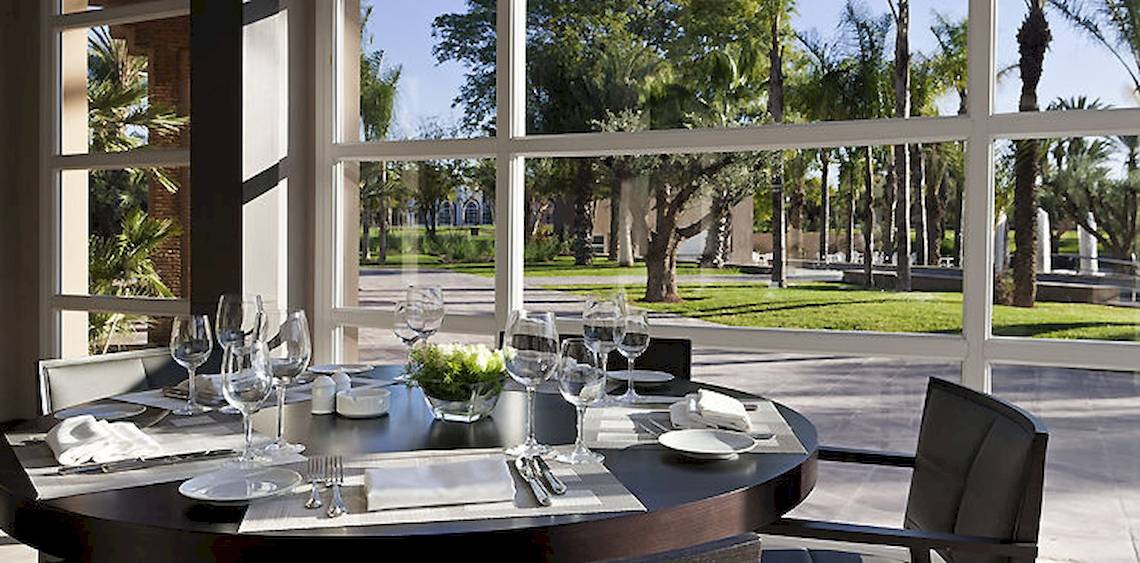 Speisesaal im Barcelo Palmeraie Hotel mit Tisch, Gläsern und Blick auf den Garten