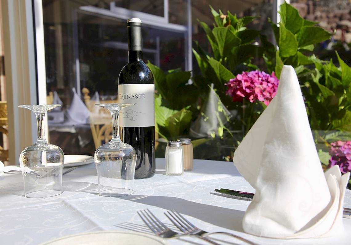 Ein Tisch im Puerto Palace Hotel mit Weinflasche, Gläsern, Besteck und Servietten.