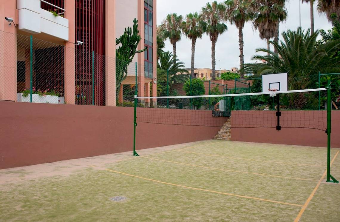 Ein Außenbereich vor dem Puerto Palace Hotel mit einem Basketballkorb und einem Volleyballnetz.
